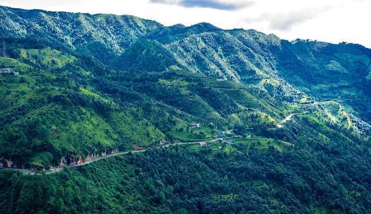 alt="Almora visit scenic view of hill town in Uttarakhand with lush green valleys and Himalayan backdrop"