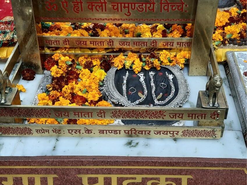 Sacred footprints (Charan Paduka) decorated with flowers at a temple during Vaishno Devi Yatra, symbolizing devotion and spiritual significance.